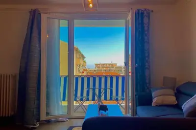a cat sitting on a couch in a living room with a window at L'Avenir du Ray in Nice