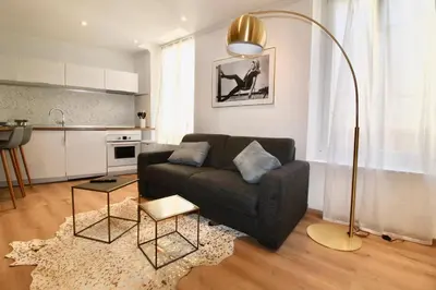 a living room with a couch and a kitchen at Lovely Apartment Heart of Golden Square Fiber Wifi in Nice