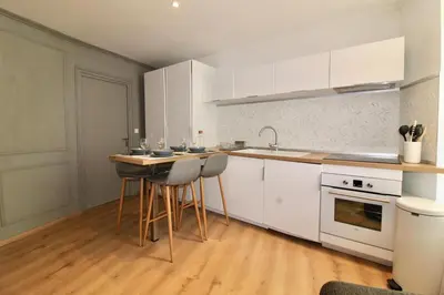 a kitchen with white cabinets and a counter with stools at Lovely Apartment Heart of Golden Square Fiber Wifi in Nice