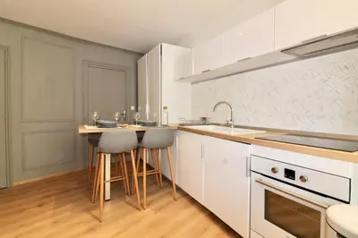 a kitchen with white cabinets and bar stools at Lovely Apartment Heart of Golden Square Fiber Wifi in Nice