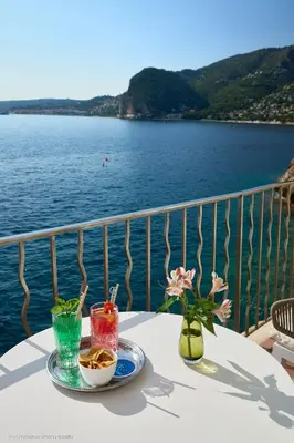 a table on a balcony with a view of the water at Hotel Cap Estel in Èze