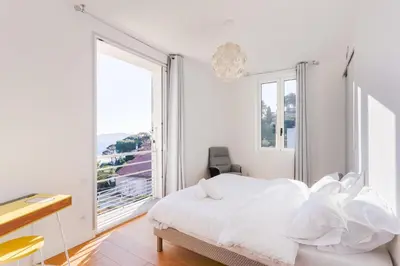 a white bedroom with a bed and a window at Villa Élégante Nice avec Vue Mer in Nice