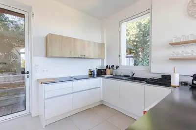 a white kitchen with white cabinets and a window at Villa Élégante Nice avec Vue Mer in Nice
