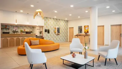 a living room with an orange couch and white chairs at Residhome Nice Aéroport in Nice
