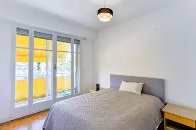a white bedroom with a bed and a window at Le Béryl in Nice