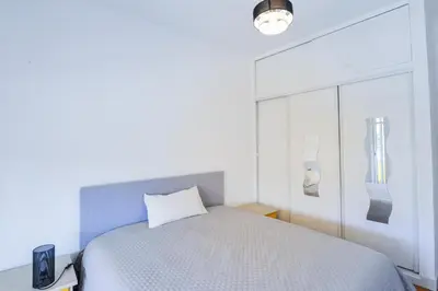 a white bedroom with a bed and a window at Le Béryl in Nice