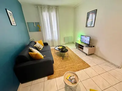 a living room with a black couch and a tv at Joli appartement spacieux à 3 min à pied de la mer in Nice