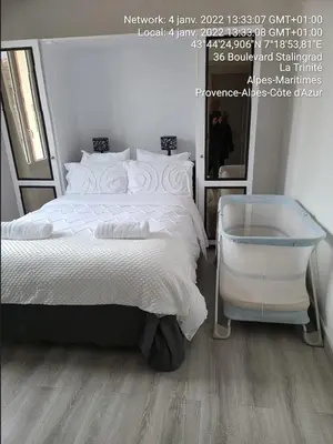 a bedroom with a white bed and a mirror at 4 logements à La Trinité proche de Nice 15 mn, Monaco 20 mn et l'Italie 30 mn 2 Chambres et 2 Studios privés et indépendants in La Trinité