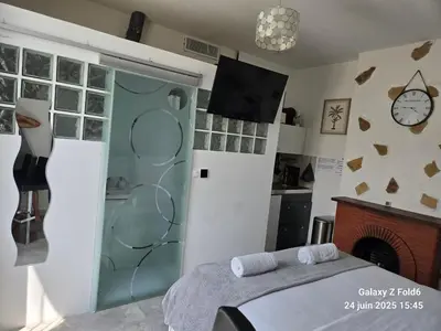 a room with a bed and a clock on the wall at 4 logements à La Trinité proche de Nice 15 mn, Monaco 20 mn et l'Italie 30 mn 2 Chambres et 2 Studios privés et indépendants in La Trinité