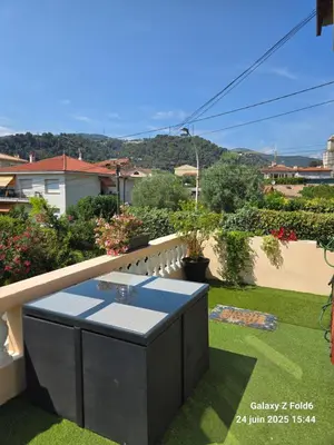 a balcony with a table on the grass at 4 logements à La Trinité proche de Nice 15 mn, Monaco 20 mn et l'Italie 30 mn 2 Chambres et 2 Studios privés et indépendants in La Trinité