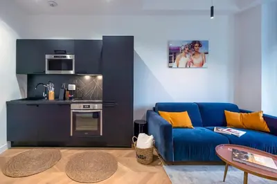 a living room with a blue couch and a kitchen at Superbe 2P Plage/ Promenade des Anglais 201 in Nice