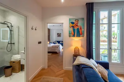 a living room with a blue couch and a bedroom at Superbe 2P Plage/ Promenade des Anglais 203 in Nice