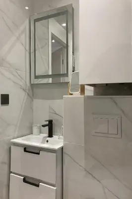a white kitchen with a sink and a mirror at Superbe studio Plage/ Promenade des Anglais 102 in Nice