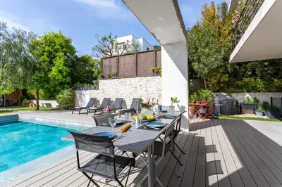 a patio with a table and chairs next to a swimming pool at Villa Les Sources VI4245 By Riviera Holiday Homes in Nice