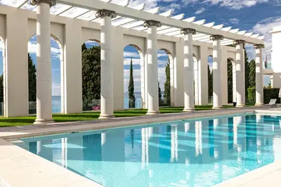 a swimming pool with white columns and a white pergola at Superbe appartement Cap de nice in Nice
