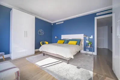 a bedroom with blue walls and a bed with yellow pillows at Superbe appartement Cap de nice in Nice