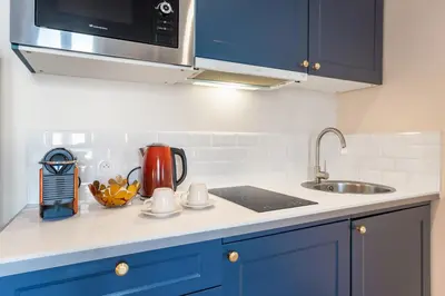 a kitchen counter with blue cabinets and a sink at Elegant Jacuzzi Loft in Central Massena in Nice