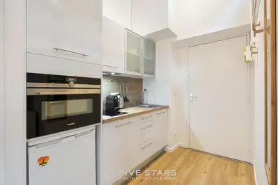 a white kitchen with white cabinets and a door at Studio Fleur FSHH in Nice