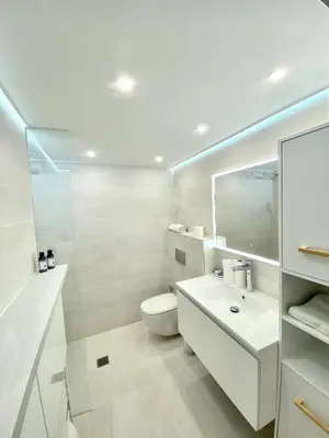 a white bathroom with a toilet and a sink at Appartement Luxe - 3 pièces avec vue mer, piscine et tennis in Nice
