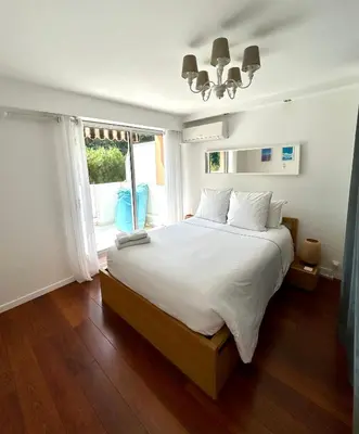 a bedroom with a large white bed and a window at Appartement Luxe - 3 pièces avec vue mer, piscine et tennis in Nice