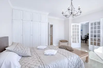 a white bedroom with a large bed and a chandelier at Horizon Blue Lux Apartment in Nice