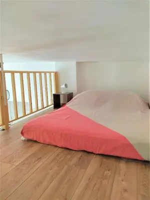 a bedroom with a bed with a red blanket on a wooden floor at 2 à 6 personnes - WELCOME TO NICE ! LOGEMENT PORT in Nice