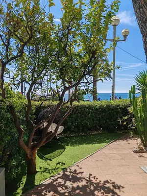 a park with palm trees in front of the beach at Garden Atlantide Promenade in Nice
