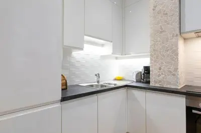 a kitchen with white cabinets and a sink at Promenade, 2pièces chic et clim avec terrasse Location éligible au Bail Mobilité Mobility Lease in Nice