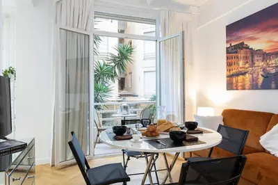 a living room with a table and a large window at Promenade, 2pièces chic et clim avec terrasse Location éligible au Bail Mobilité Mobility Lease in Nice