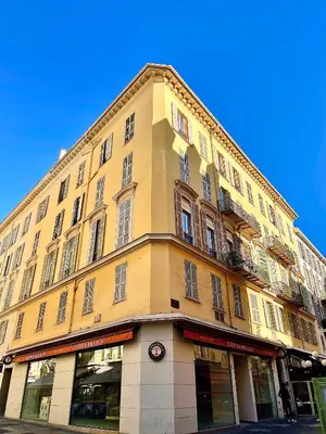 a tall yellow building with a clock on it at Un havre de paix et de calme en plein centre de Massena in Nice