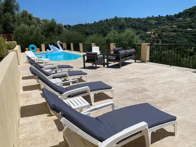 a row of lounge chairs next to a swimming pool at Villa avec piscine chauffée Nice collines in Nice