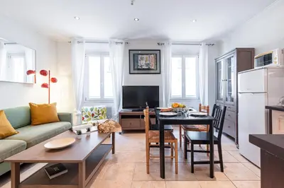 a living room with a couch and a table and a kitchen at FEEL HOME - BARILLERIE in Nice