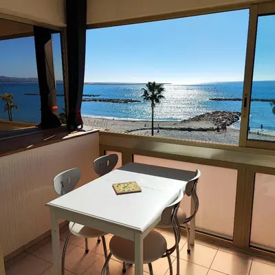 a table and chairs in a room with a view of the ocean at Grand studio bord de mer- accès direct aux plages in Saint-Laurent-du-Var