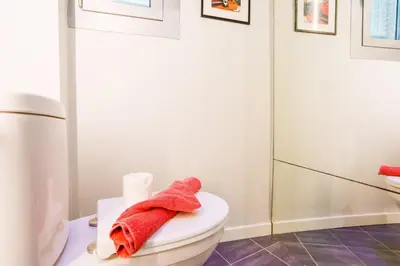 a bathroom with a toilet with red towels on it at LE TIVOLI AP4264 By Riviera Holiday Homes in Nice