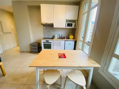a kitchen with a wooden table and two chairs at Le Delfino PORT DE NICE in Nice