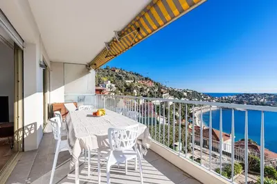 a balcony with a table and chairs and the ocean at Villefranche Sur Mer:Appartement-villa, Vue mer, jardin, parking. in Villefranche-sur-Mer