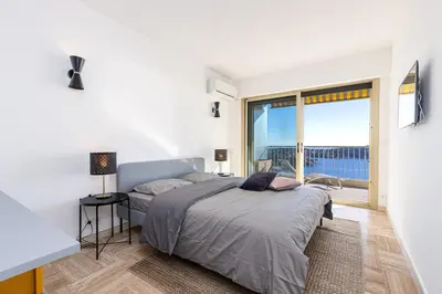 a bedroom with a bed with a view of the ocean at Villefranche Sur Mer:Appartement-villa, Vue mer, jardin, parking. in Villefranche-sur-Mer