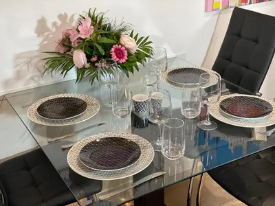 a glass table with plates and glasses and a vase with flowers at Central Lamartine Flat - Brand New in Nice