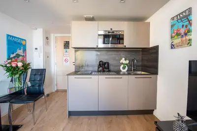 a kitchen with white cabinets and a table and chairs at Central Lamartine Flat - Brand New in Nice