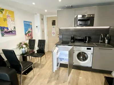 a kitchen with a washing machine and a table with chairs at Central Lamartine Flat - Brand New in Nice