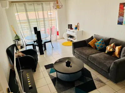 a living room with a couch and a table at L Arieta - Appartement 3 pièces vue mer, parking & piscine in Nice