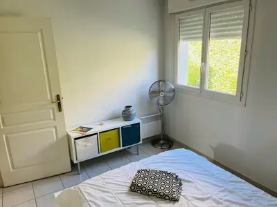 a bedroom with a bed and a fan and a window at L Arieta - Appartement 3 pièces vue mer, parking & piscine in Nice