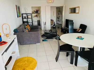 a living room with a table and a couch at L Arieta - Appartement 3 pièces vue mer, parking & piscine in Nice