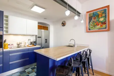 a kitchen with blue cabinets and a counter with stools at Maison Bianchi - Old Town Flower market in Nice