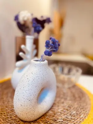 a glass vase filled with dried flowers on a table at Appart Hotel Jaures - Boutique apartments in Nice