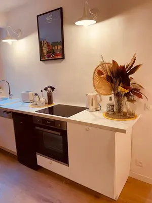 a wooden table with chairs and a vase with flowers at Appart Hotel Jaures - Boutique apartments in Nice