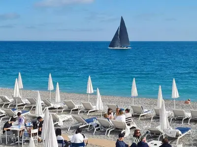 a group of people sitting on a beach with a sail boat at Le Nid Blanc Nice Centre in Nice