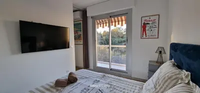 a bedroom with a tv and a bed and a window at HOME ET HOLIDAY Le Petit Manseng in Nice