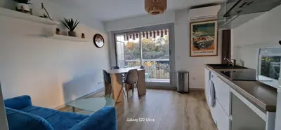 a living room with a blue couch and a kitchen at HOME ET HOLIDAY Le Petit Manseng in Nice