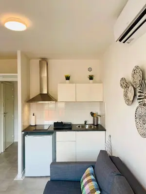 a living room with a couch and a kitchen at Nice Promenade 2 in Nice